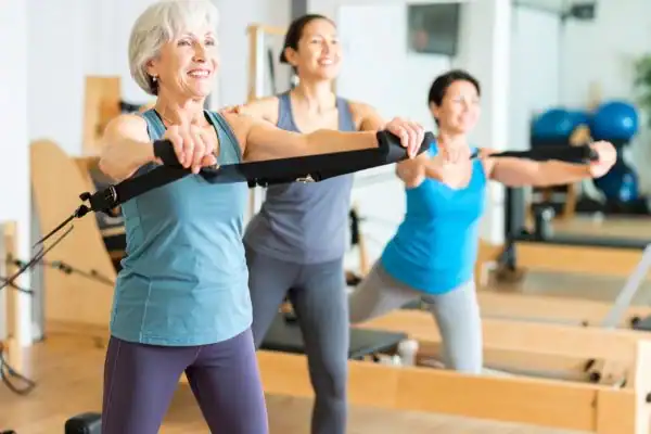 Toning Arms After 60: Empowering Womens Fitness Through Effective Weight Training 2 older woman doing weight training Rickmansworth and resistance in the gym to tone upper arms